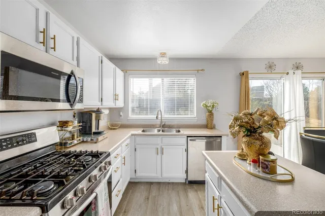 a kitchen with stainless steel appliances a stove a sink cabinets and a dining table