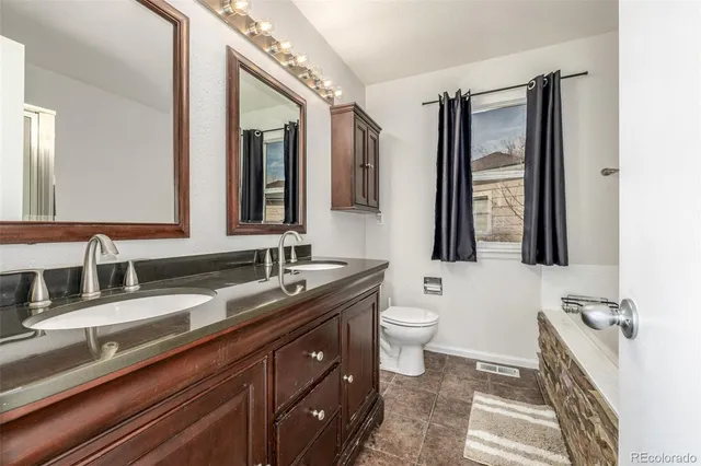 a bathroom with a granite countertop sink mirror and toilet