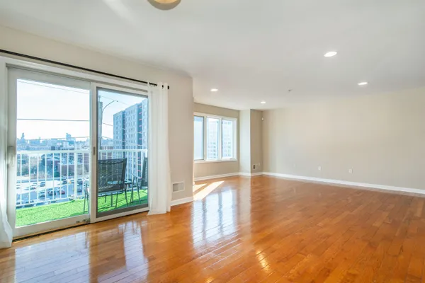 a view of an empty room with wooden floor and a window