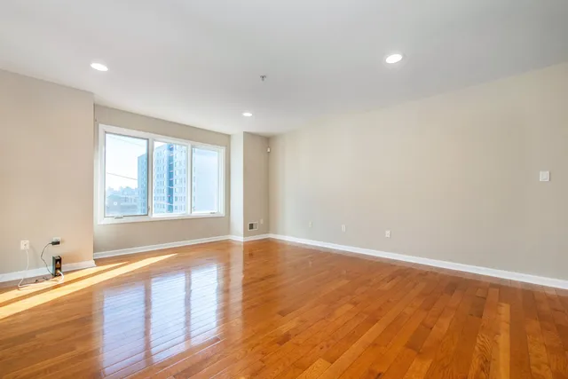 a view of an empty room with wooden floor and a window