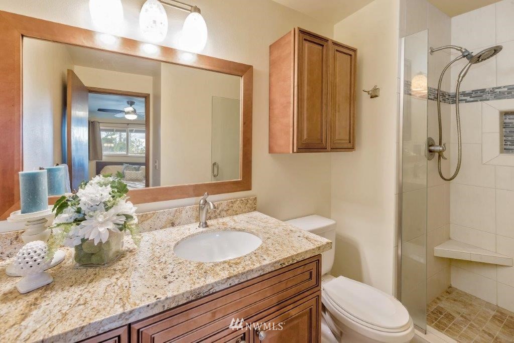 12525 Southeast 99th Street Renton, WA 98056 - Photo 18 of 33 a bathroom with a granite countertop sink a toilet and a shower