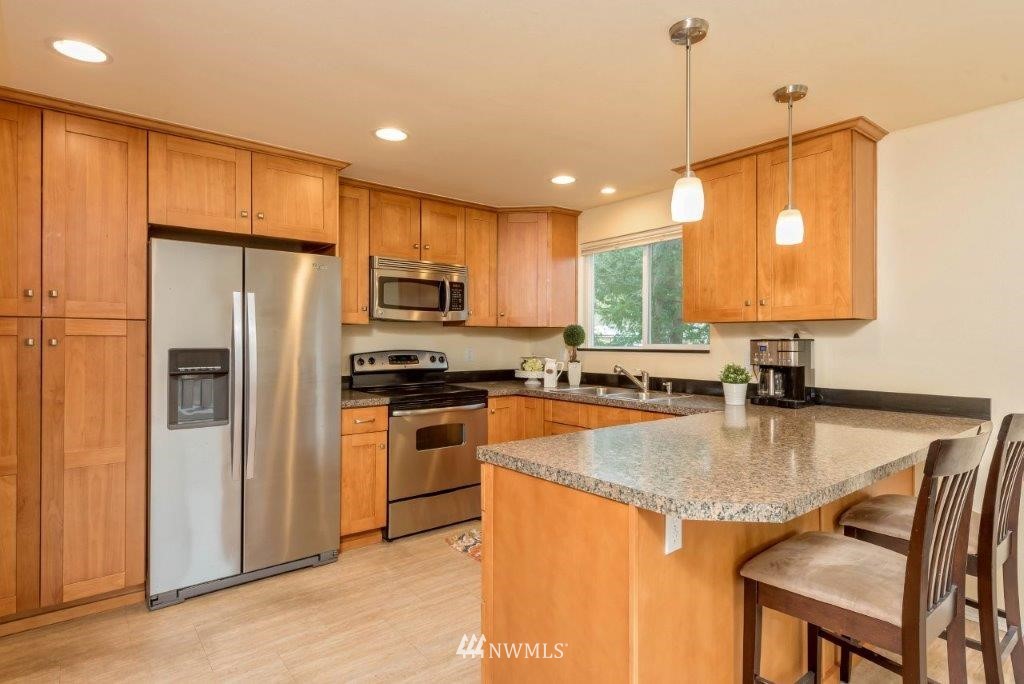 12525 Southeast 99th Street Renton, WA 98056 - Photo 8 of 33 a kitchen with stainless steel appliances granite countertop a refrigerator a stove top oven a sink and dishwasher