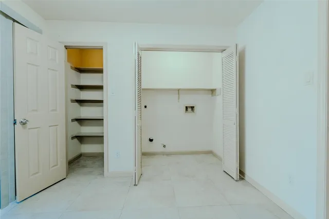 a view of an empty room with closet and a window