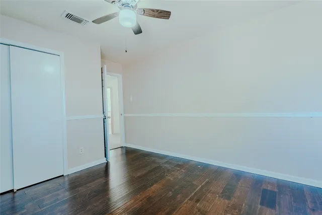 an empty room with wooden floor and fan