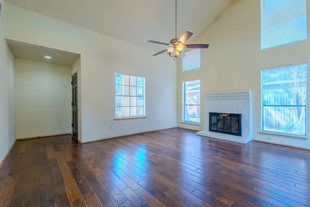 an empty room with wooden floor a chandelier fan and a fireplace