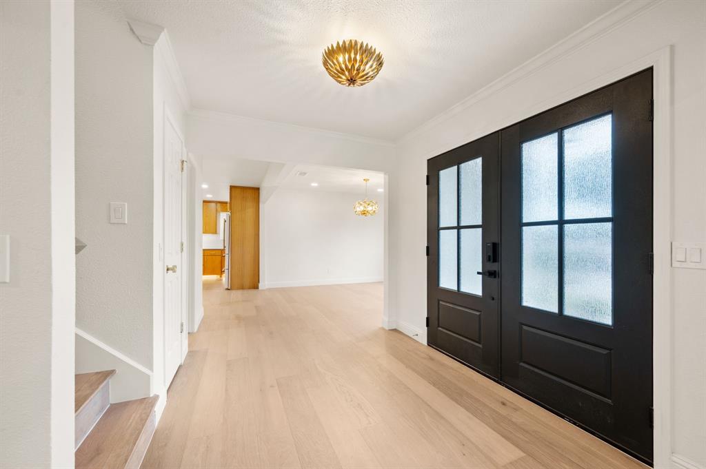 6403 Genstar Lane Dallas, TX 75252 - Photo 5 of 34 Double entry doors with frosted glass panels, crown molding, wood-finish flooring, and a decorative flush-mount ceiling fixture