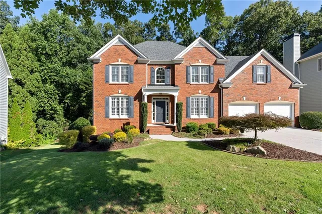 a front view of a house with a yard and trees