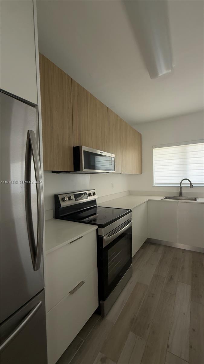 2000 Southwest 13th Court Miami, FL 33145 - Photo 6 of 22 a kitchen with stainless steel appliances granite countertop a refrigerator a sink a stove and white cabinets