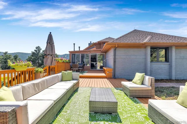 a view of a patio with couches and a table and chairs with wooden floor and fence