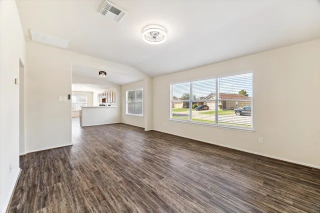 an empty room with wooden floor and windows