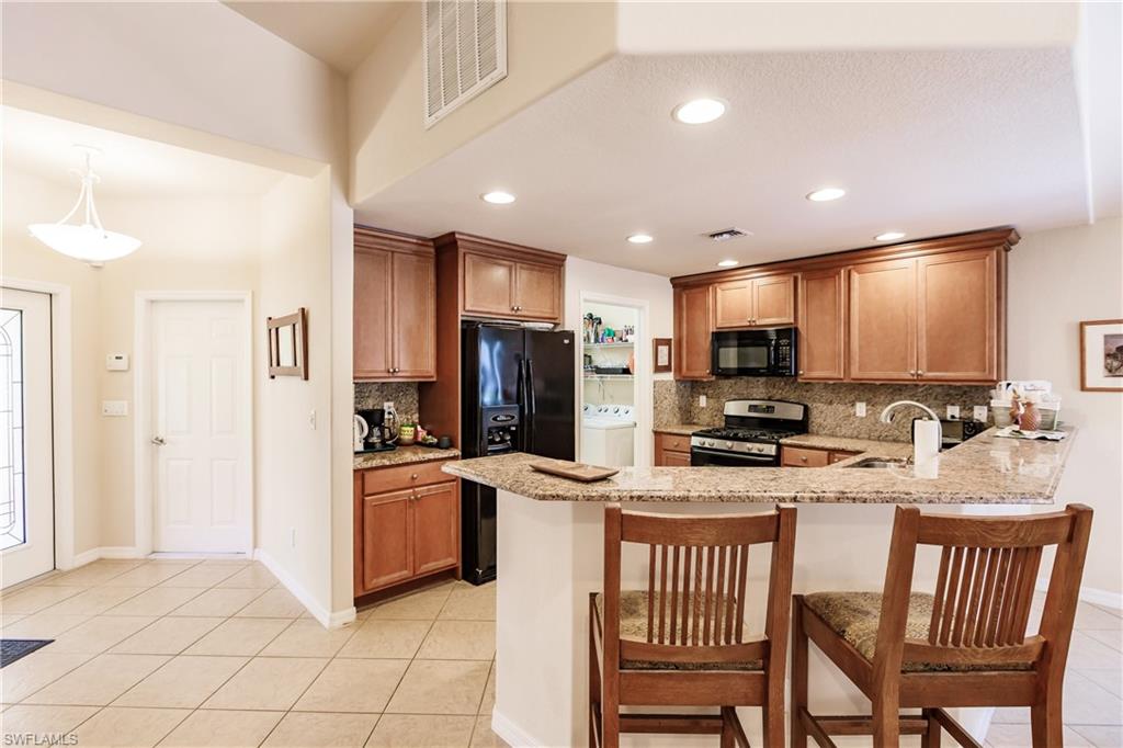19628 Villa Rosa Loop Estero, FL 33967 - Photo 4 of 25 a kitchen with stainless steel appliances kitchen island granite countertop a refrigerator and microwave