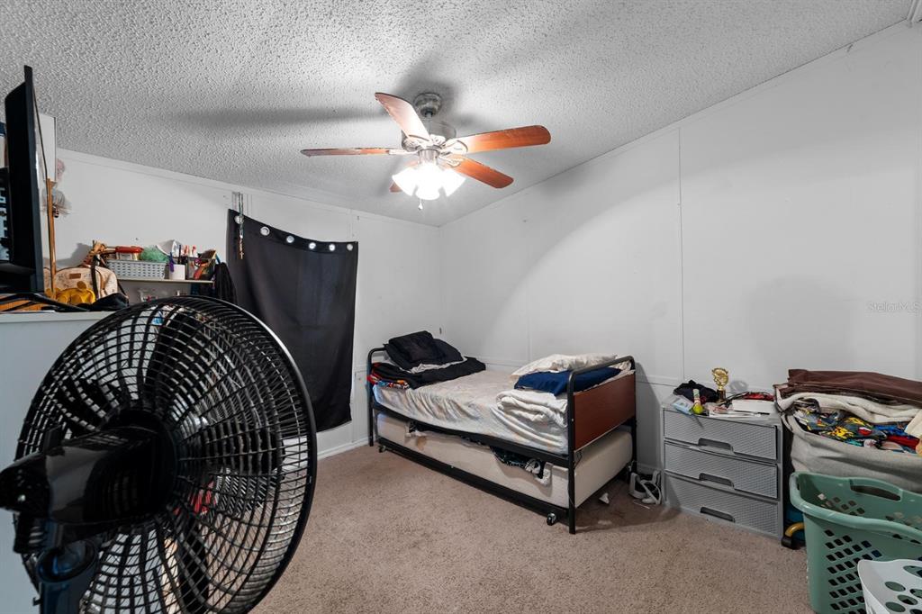 17558 Caufield Road Spring Hill, FL 34610 - Photo 12 of 20 a bedroom with a bed and a chandelier