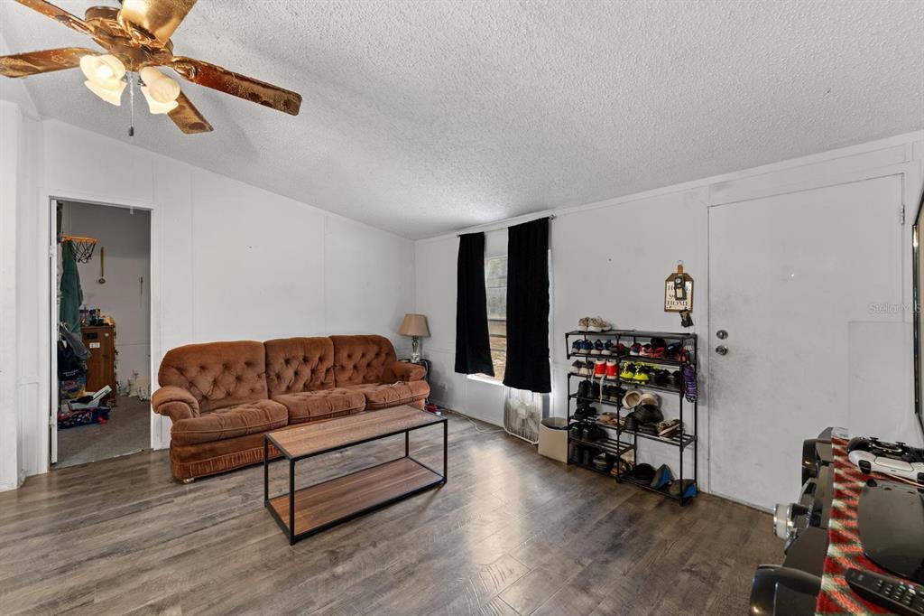 17558 Caufield Road Spring Hill, FL 34610 - Photo 4 of 20 a living room with furniture a flat screen tv and a dresser with wooden floor