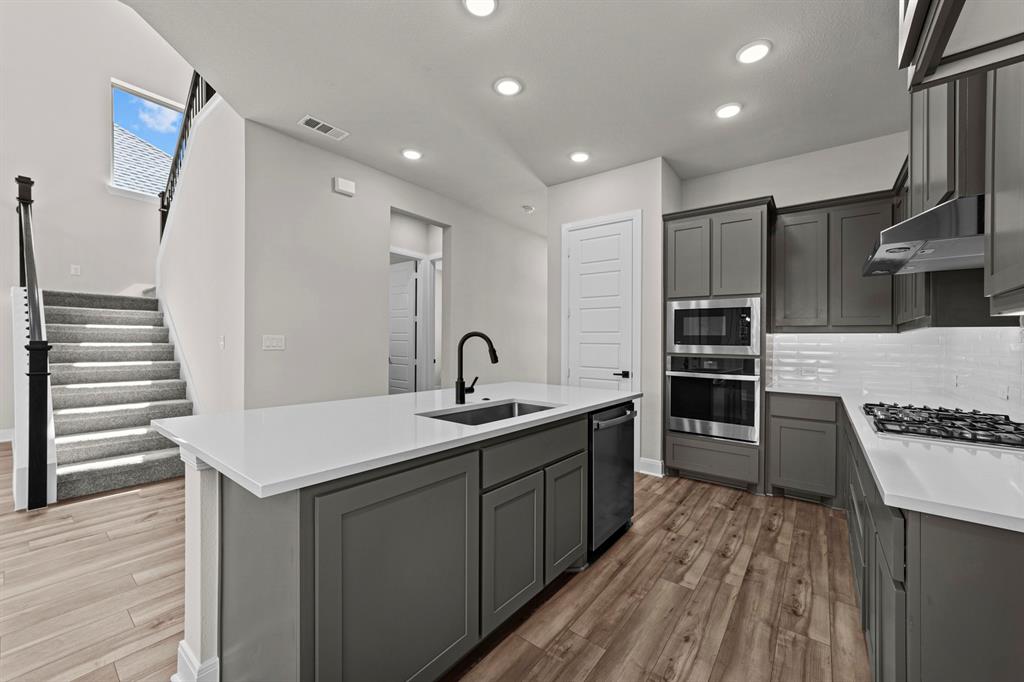 2044 Cuellar Way Van Alstyne, TX 75495 - Photo 22 of 30 a kitchen with cabinets and wooden floor