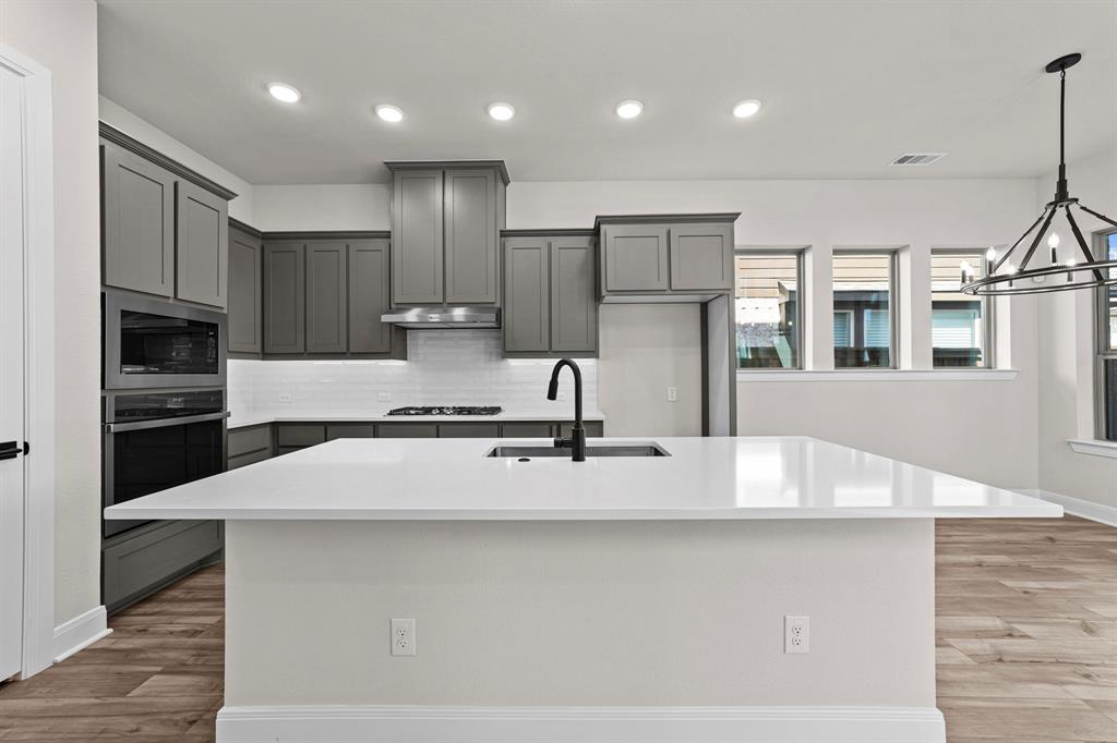 2044 Cuellar Way Van Alstyne, TX 75495 - Photo 23 of 30 a large kitchen with stainless steel appliances kitchen island a large counter top and a stove top oven