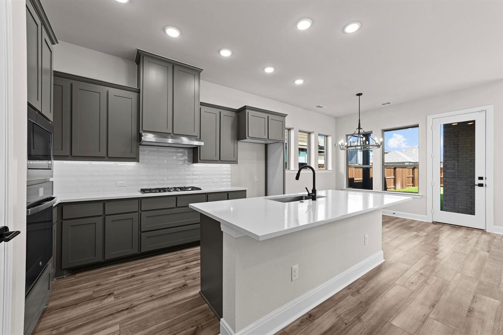 2044 Cuellar Way Van Alstyne, TX 75495 - Photo 24 of 30 a large kitchen with stainless steel appliances kitchen island granite countertop a large stove a refrigerator a sink and dishwasher with wooden floor