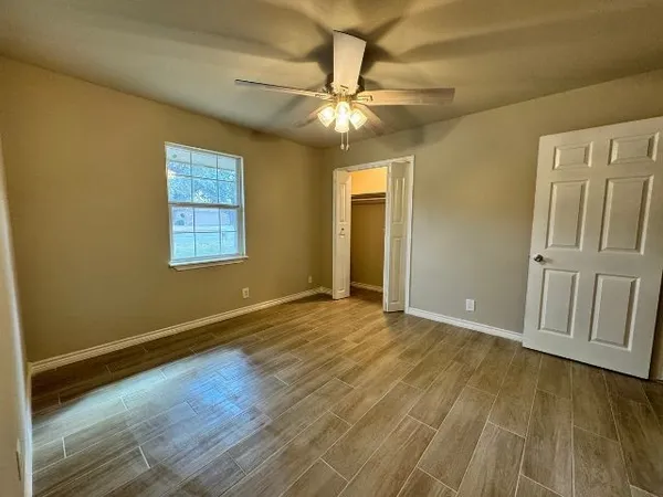 an empty room with wooden floor and fan