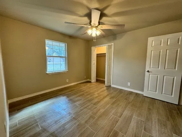 an empty room with wooden floor and fan