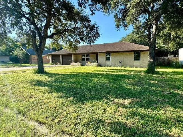 a white house with a big yard and large trees