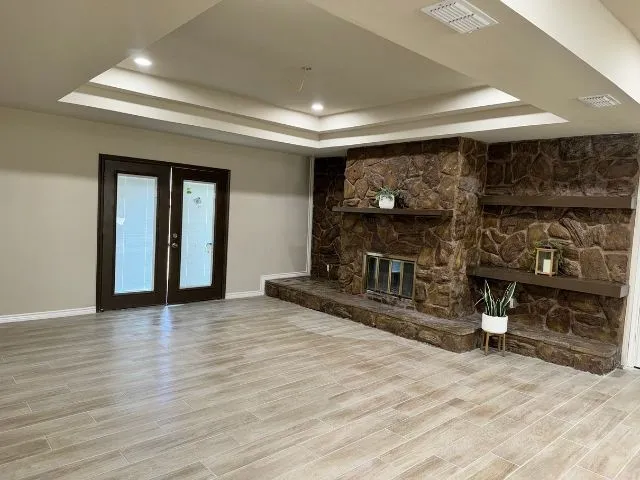 a view of an empty room with wooden floor and a fireplace
