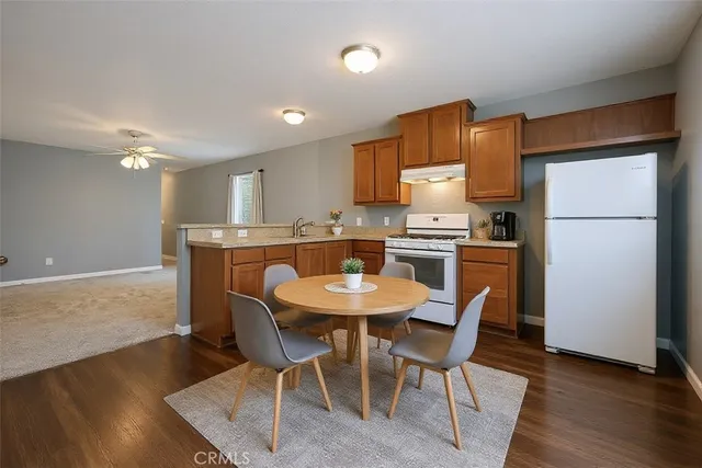 a kitchen with stainless steel appliances granite countertop a dining table chairs refrigerator and sink