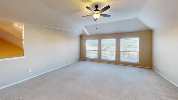 an empty room with windows and ceiling fan