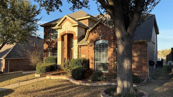 a view of a brick house with large windows and a small yard