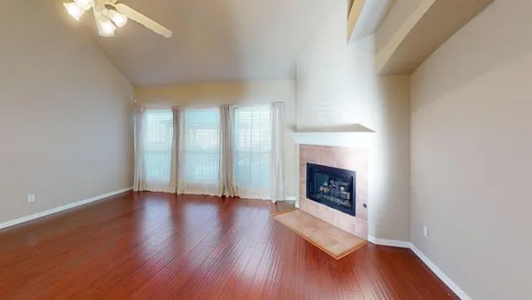 a view of an empty room with wooden floor fireplace and a window