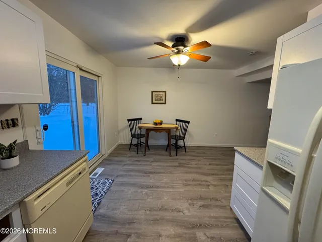 a living room with a dining table chairs and a refrigerator