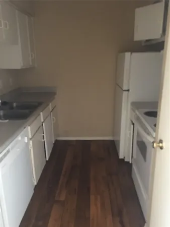 a kitchen with a sink a refrigerator and wooden floor