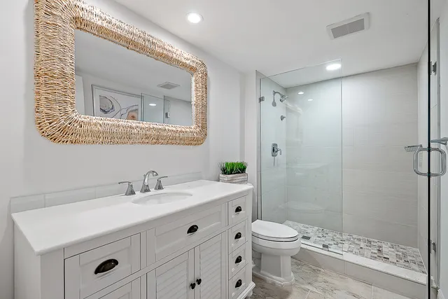 a bathroom with a toilet a sink a mirror and a shower