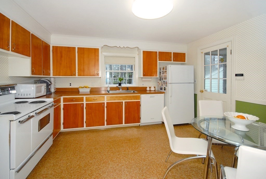 48 Wilson Road Concord, MA 01742 - Photo 14 of 41 a kitchen with stainless steel appliances a stove a refrigerator a sink a dining table and chairs