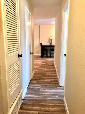 a view of a hallway with wooden floor and a bathroom