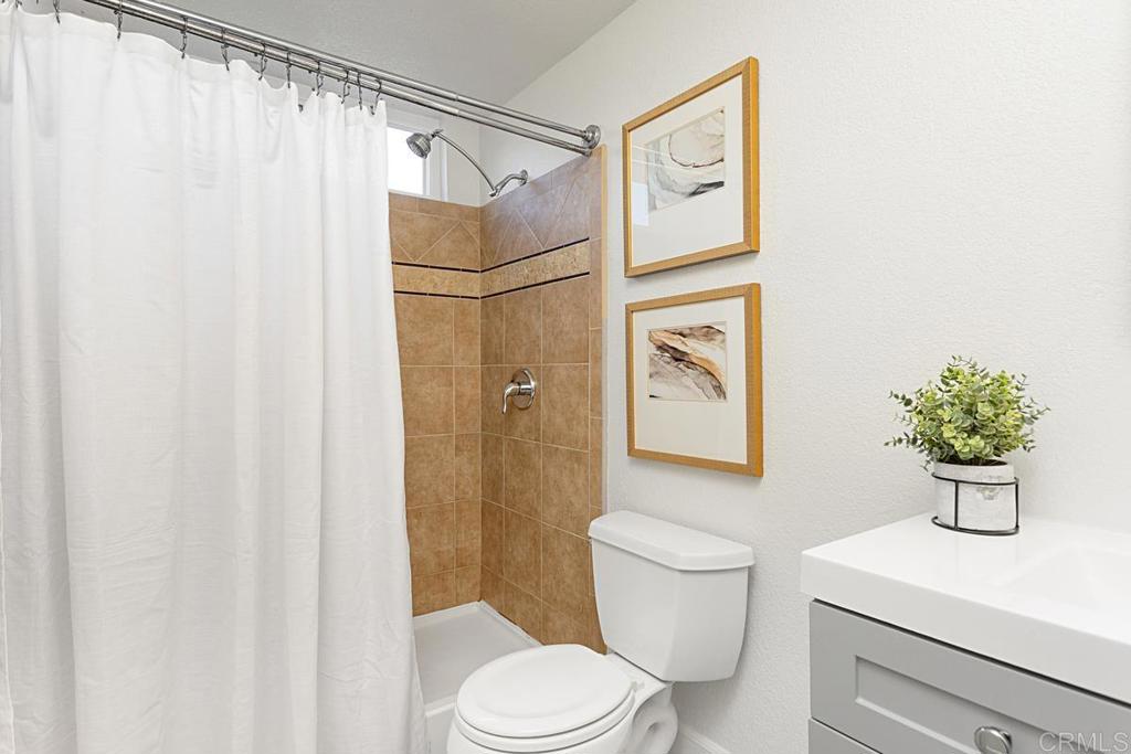 1081 Tylee Street Vista, CA 92083 - Photo 18 of 26 a bathroom with a toilet a sink and curtain