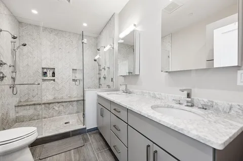 a bathroom with a granite countertop sink a toilet and shower