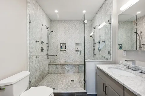 a bathroom with a granite countertop sink a toilet and shower