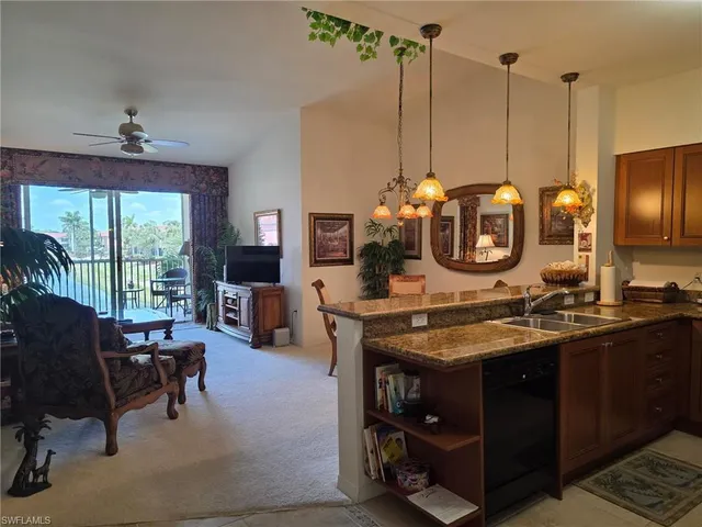 a view of a kitchen with kitchen island stainless steel appliances a stove center island and couches