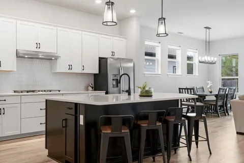 a kitchen with kitchen island a dining table chairs stainless steel appliances and cabinets
