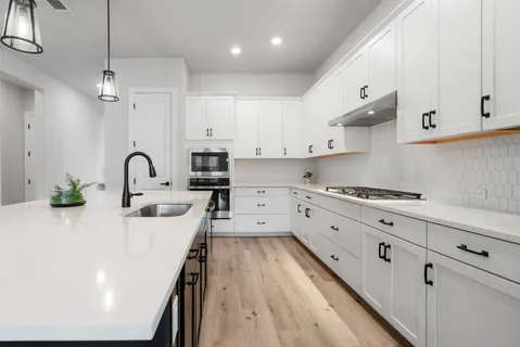 a large kitchen with cabinets a sink a center island and stainless steel appliances