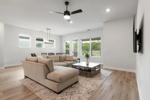 a large kitchen with white cabinets a sink dishwasher and a stove with wooden floor