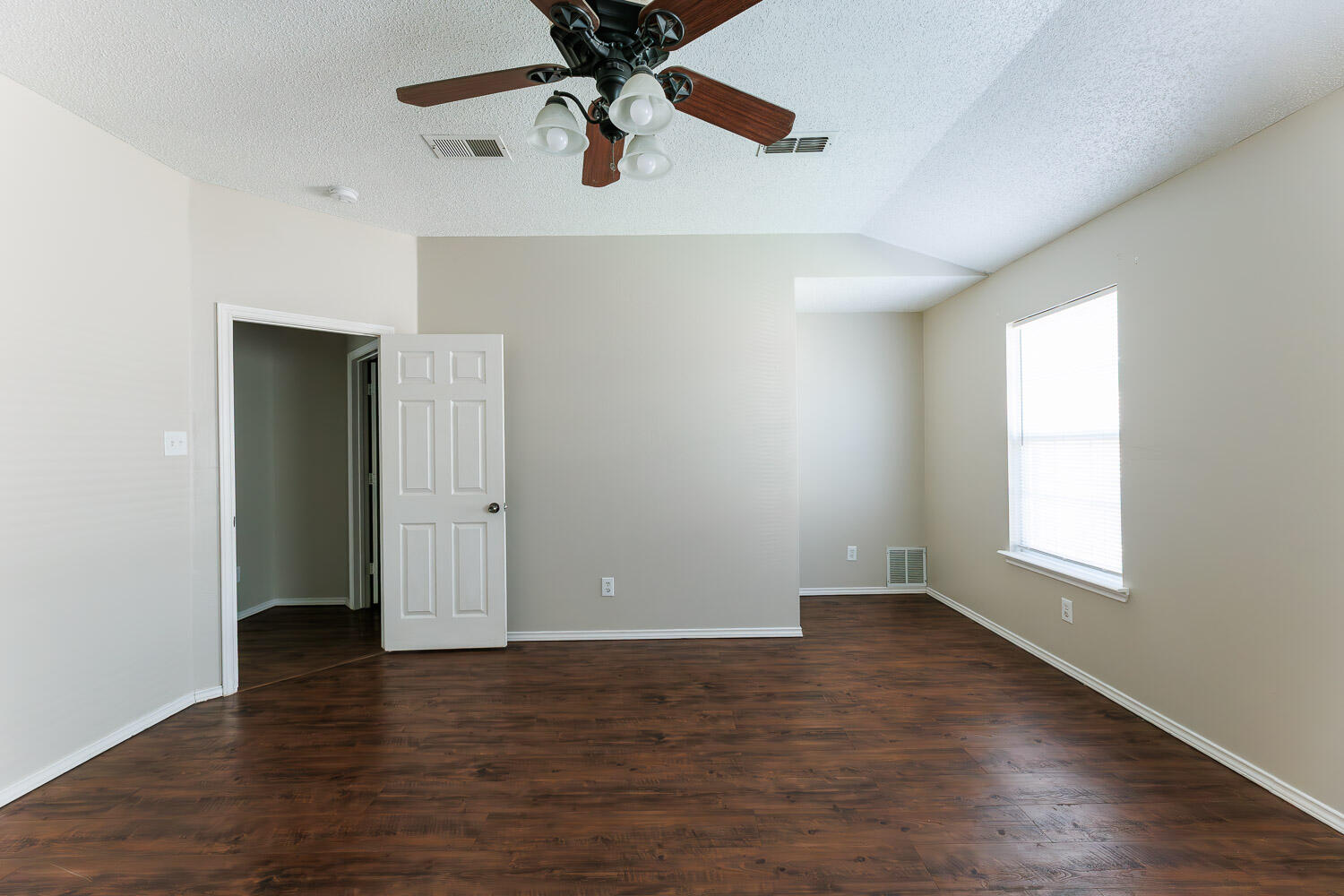 6704 87th Street Lubbock, TX 79424 - Photo 29 of 49 an empty room with wooden floor chandelier fan and windows
