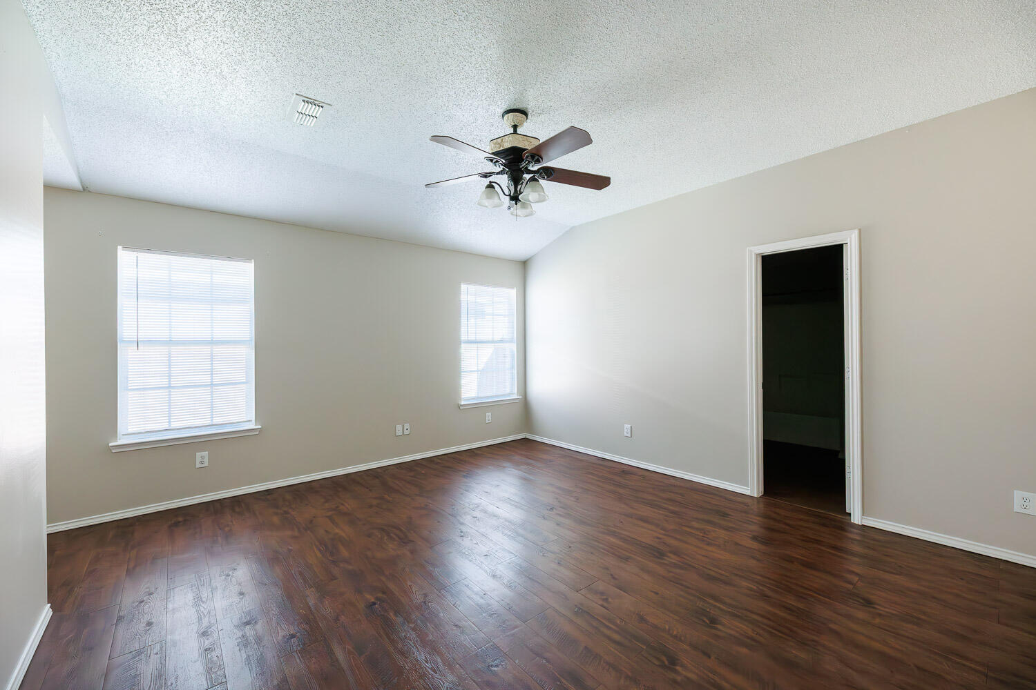 6704 87th Street Lubbock, TX 79424 - Photo 30 of 49 an empty room with wooden floor chandelier fan and windows