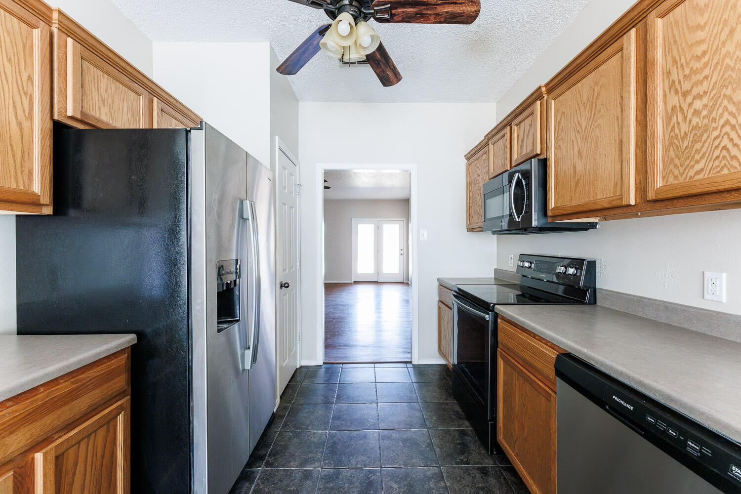 6704 87th Street Lubbock, TX 79424 - Photo 8 of 49 a kitchen with stainless steel appliances granite countertop a refrigerator a stove and a sink with wooden floor