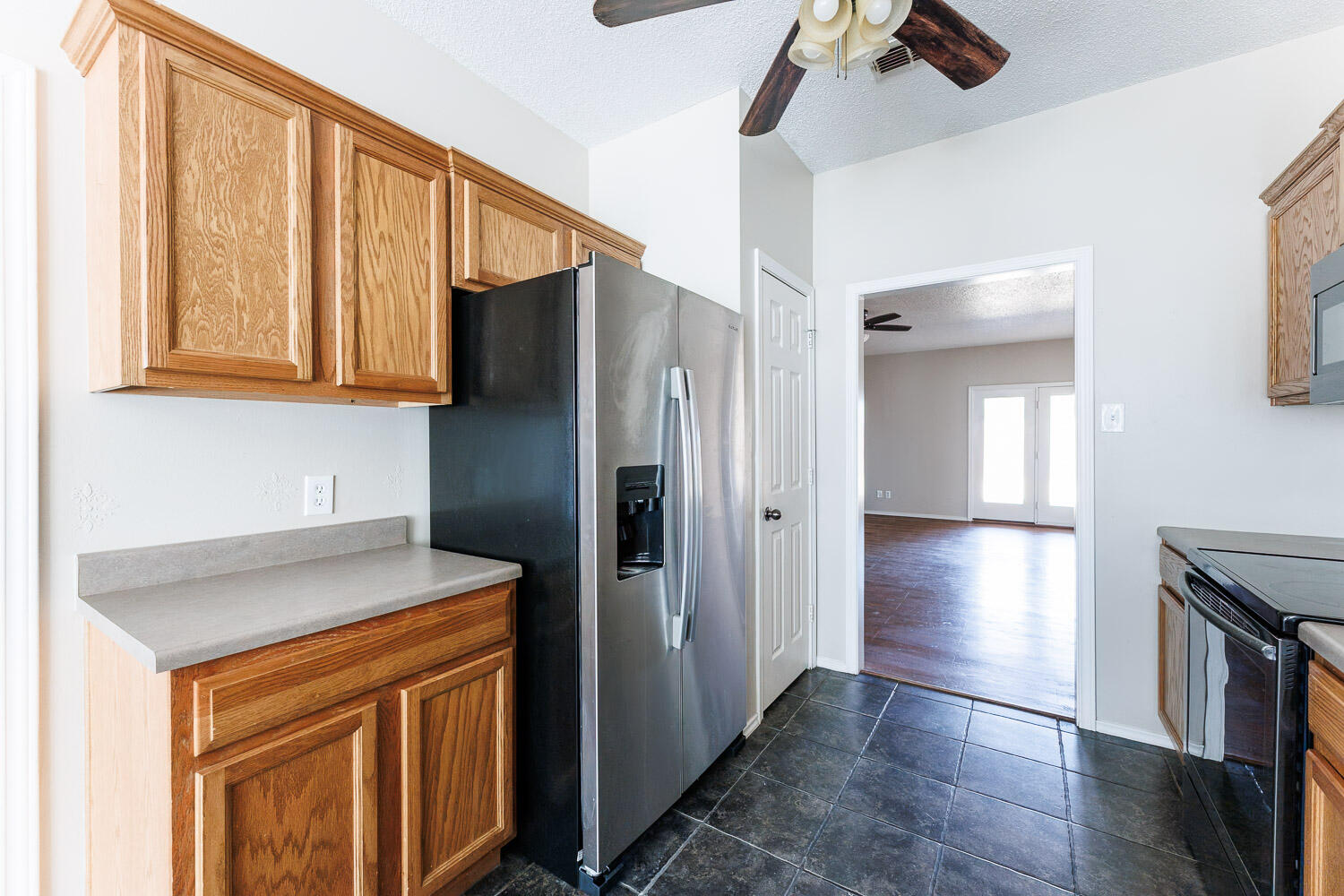 6704 87th Street Lubbock, TX 79424 - Photo 9 of 49 a kitchen with stainless steel appliances granite countertop a refrigerator a stove and a sink with wooden floors