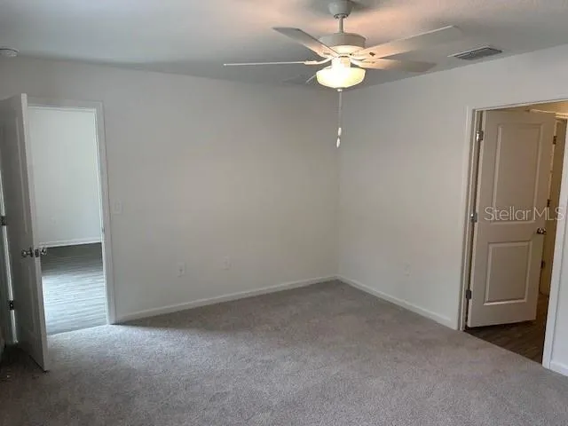 an empty room with a ceiling fan and a window
