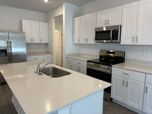 a kitchen with white cabinets and black appliances
