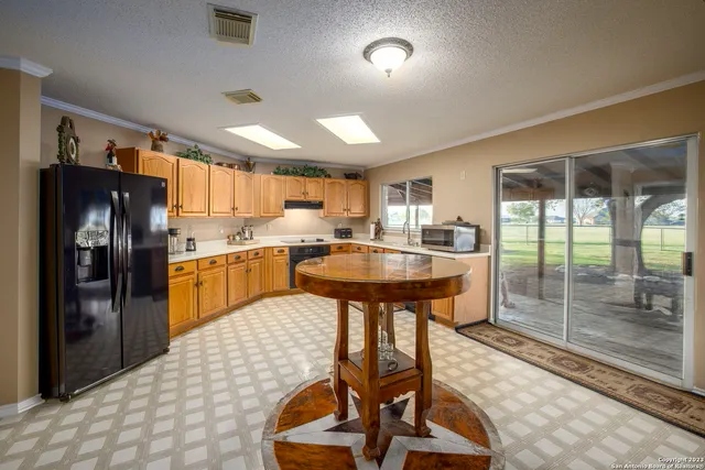 a kitchen with stainless steel appliances kitchen island granite countertop a refrigerator a sink a stove and white cabinets with wooden floor