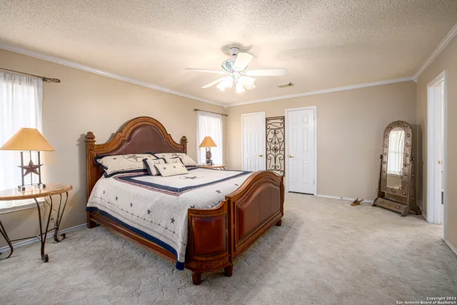a spacious bedroom with a bed a chandelier and mirror