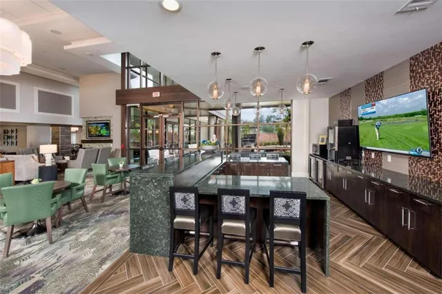 a view of a dining room and livingroom with furniture wooden floor a rug a flat screen tv a painting and a chandelier