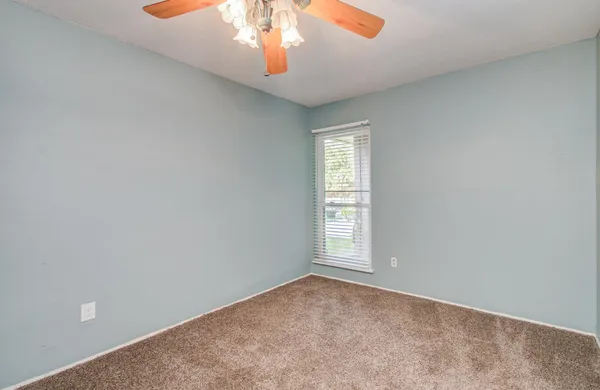 an empty room with a chandelier fan and windows
